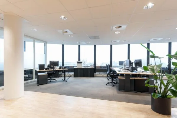 Modern kantoor met werkplekken, grote ramen en een kamerplant aan de 1e Hogeweg.