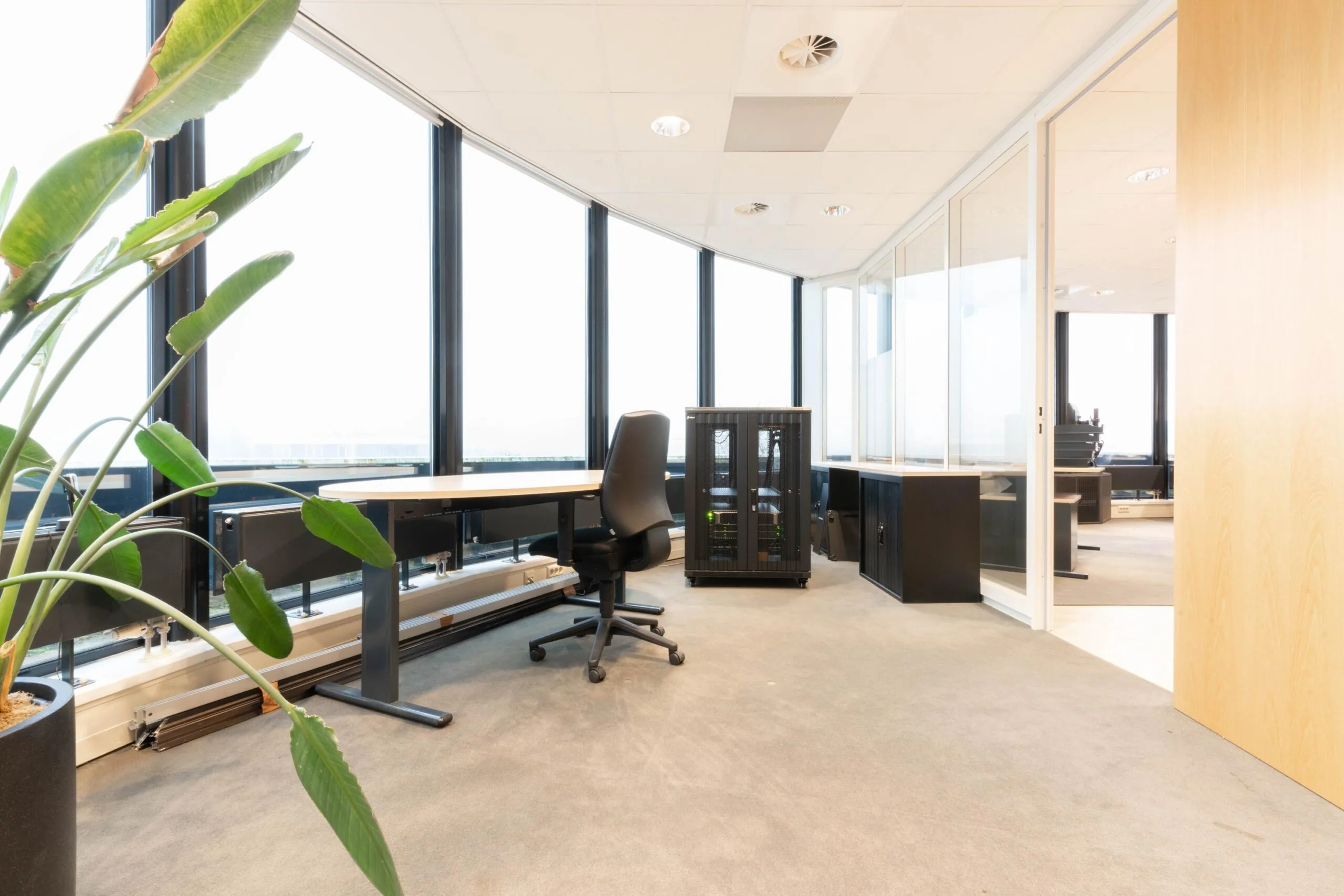 Modern kantoorinterieur aan de 1e Hogeweg met bureaus, bureaustoel, serverkast en grote ramen met veel lichtinval.