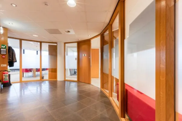 Moderne kantoorhal met glazen wanden, houten kozijnen en tegelvloer aan de 1e Hogeweg.