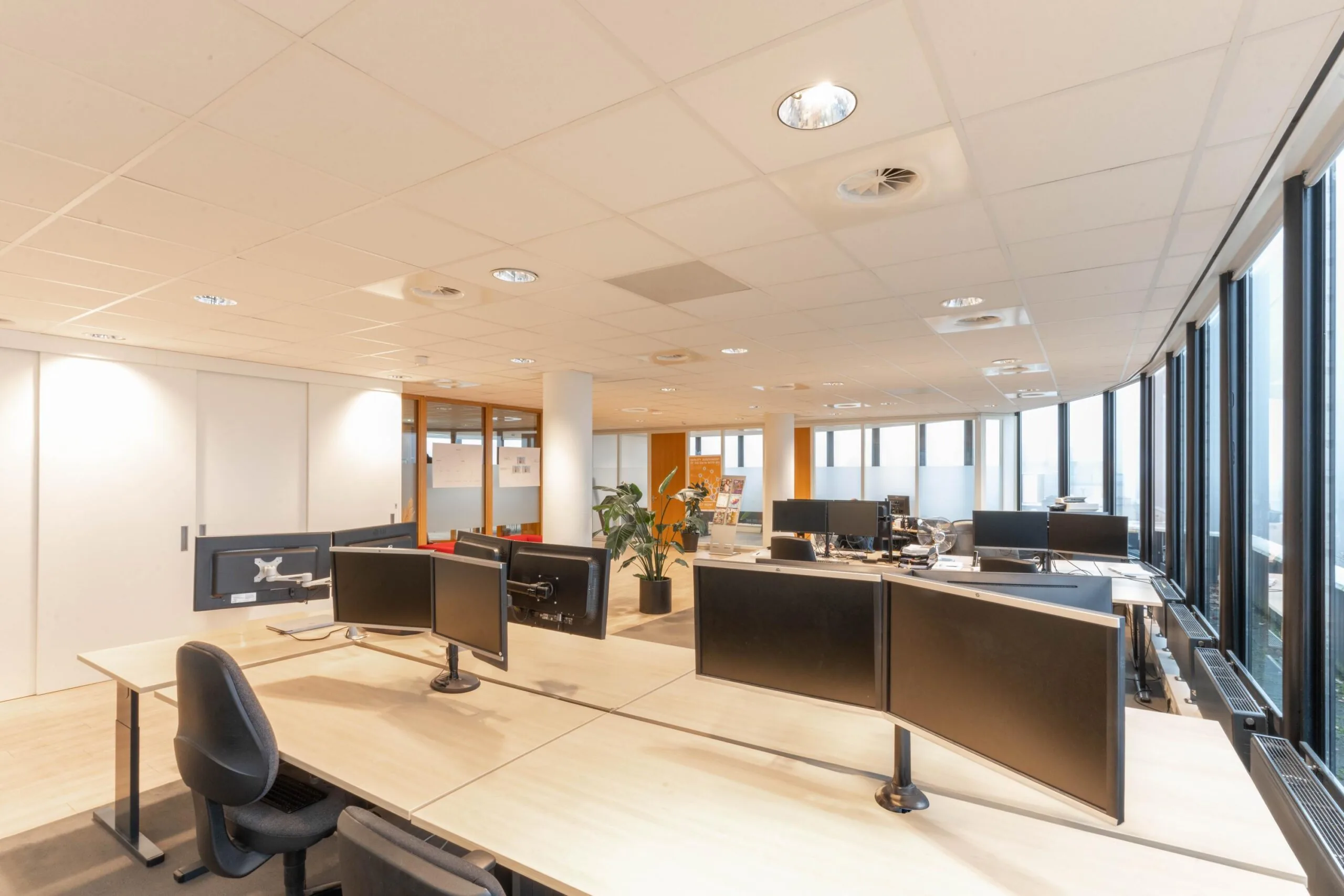 Modern en licht open kantoor aan de 1e Hogeweg met werkplekken, computers en grote ramen.
