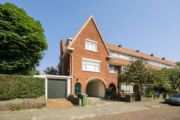 Rijwoning met rode dakpannen aan de Jacques Perkstraat met doorgang naar Ondernemersplein De Regenboog.