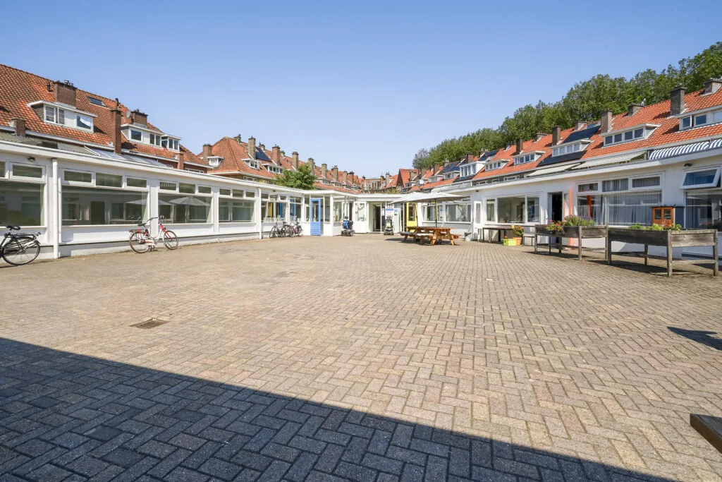 Binnenplaats aan de Jacques Perkstraat met omliggende lage bebouwing, rode dakpannen en fietsen voor de gevels.