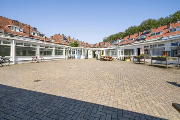 Binnenplaats aan de Jacques Perkstraat met omliggende lage bebouwing, rode dakpannen en fietsen voor de gevels.