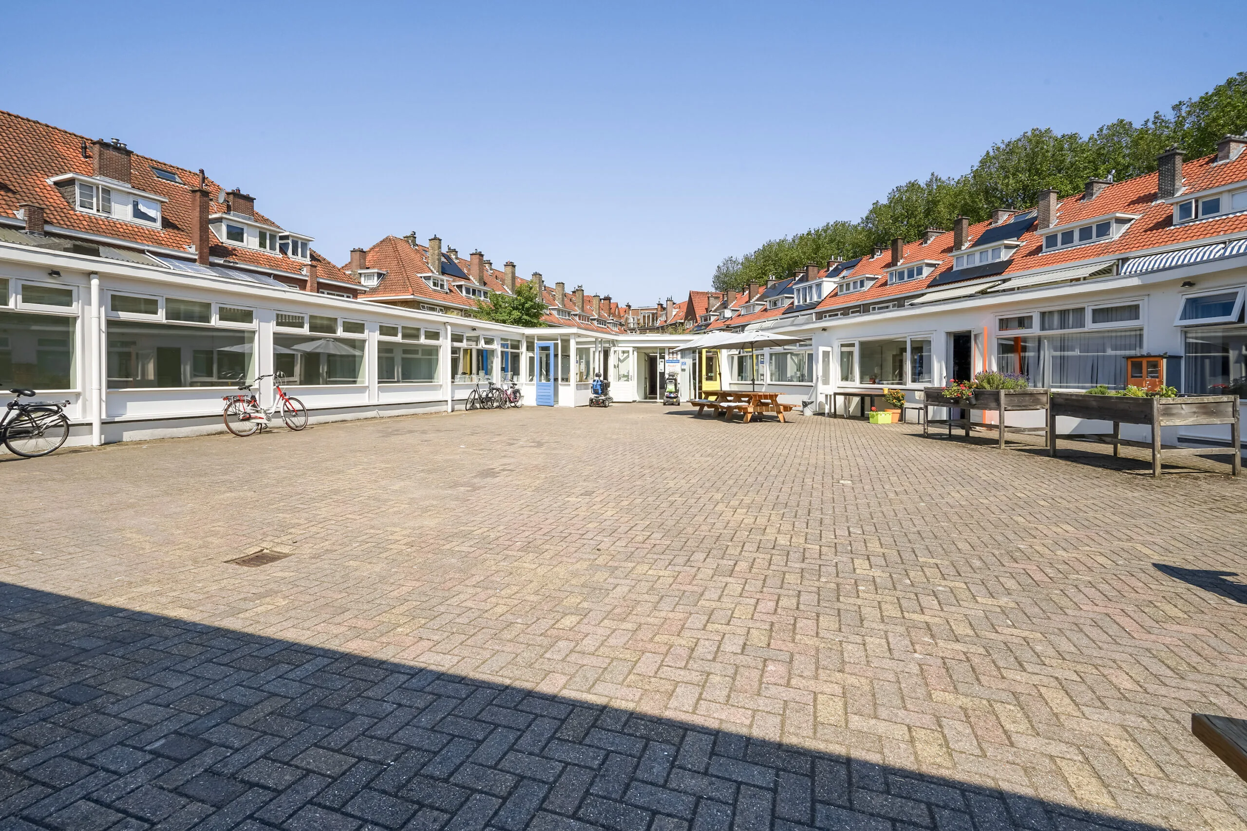 Binnenplaats aan de Jacques Perkstraat met omliggende lage bebouwing, rode dakpannen en fietsen voor de gevels.