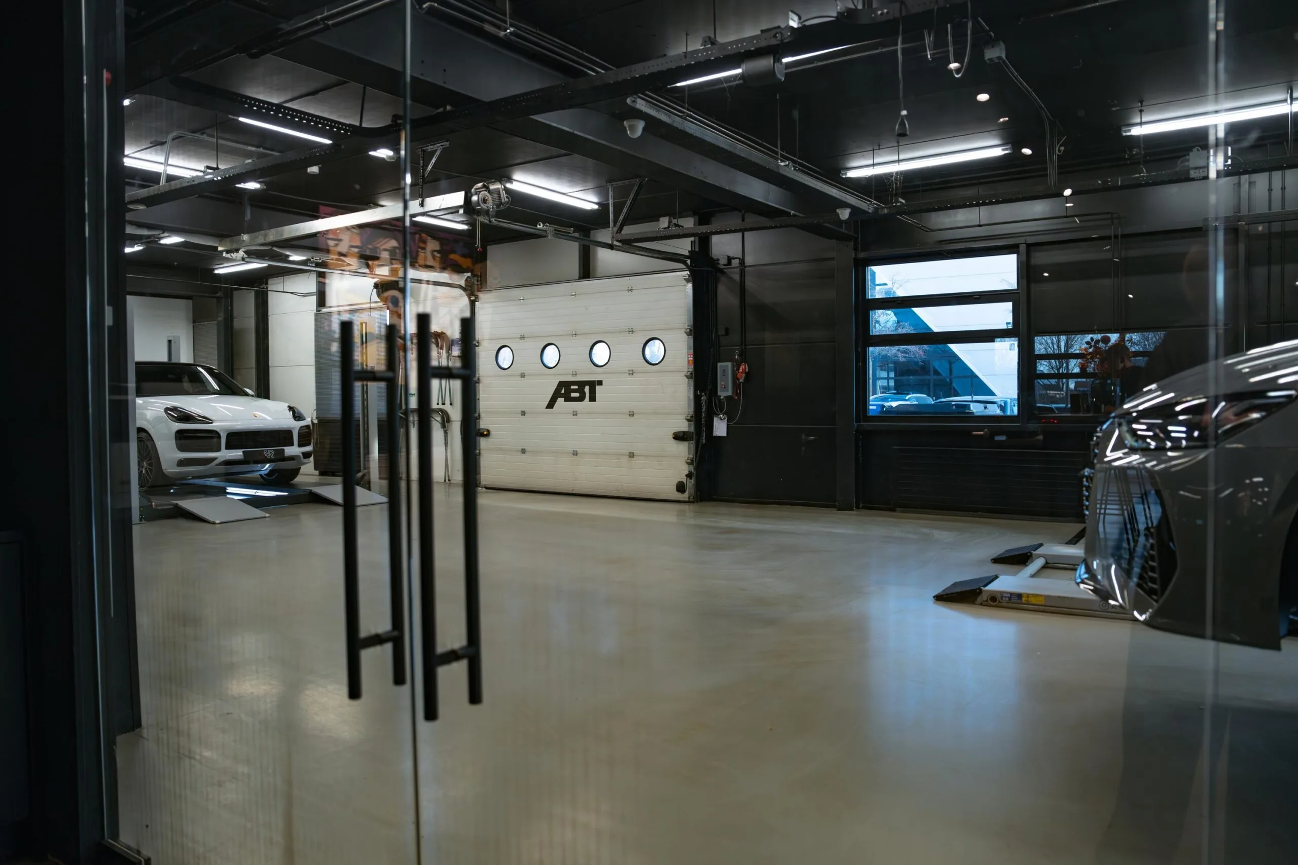 Moderne autowerkplaats aan de Frankfurtstraat met luxe auto's en een ABT-garagedeur.