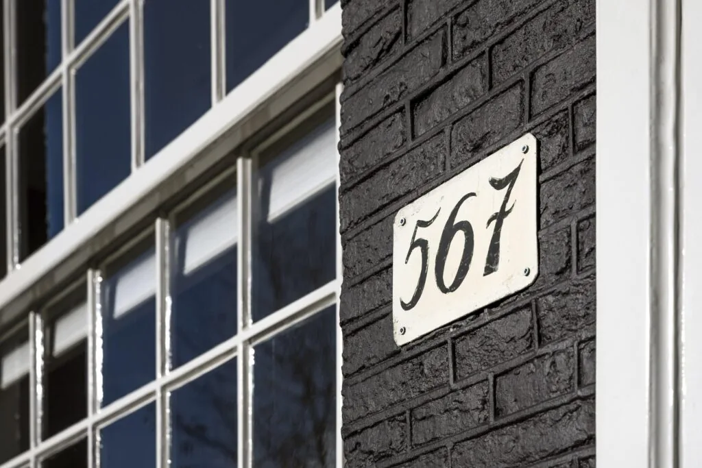 Huisnummer 567 op een zwart bakstenen gevel aan de Herengracht.
