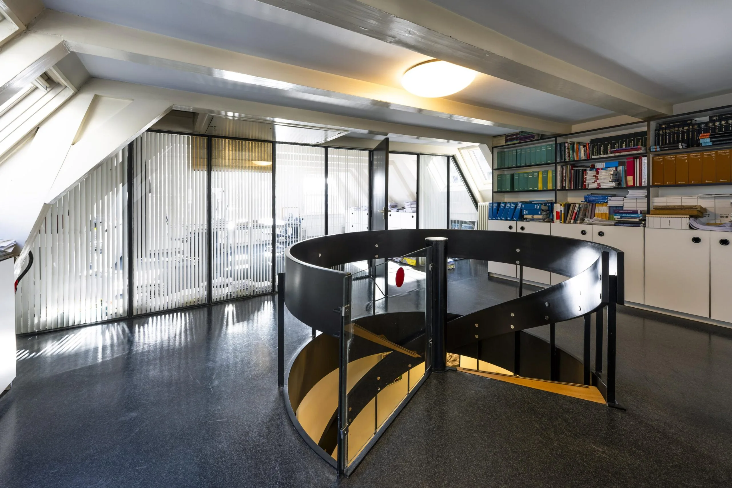 Moderne kantoorruimte aan de Herengracht met wenteltrap, boekenkasten en glazen wanden met verticale lamellen.