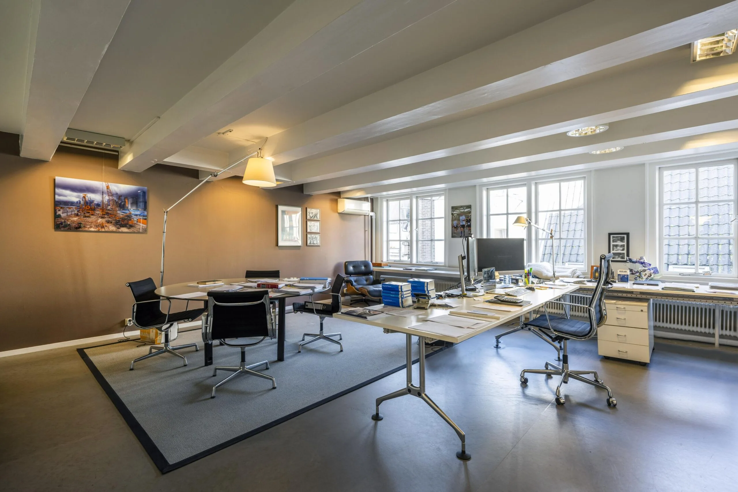 Modern kantoorinterieur aan de Herengracht met bureaus, vergadertafel en grote ramen die veel daglicht binnenlaten.