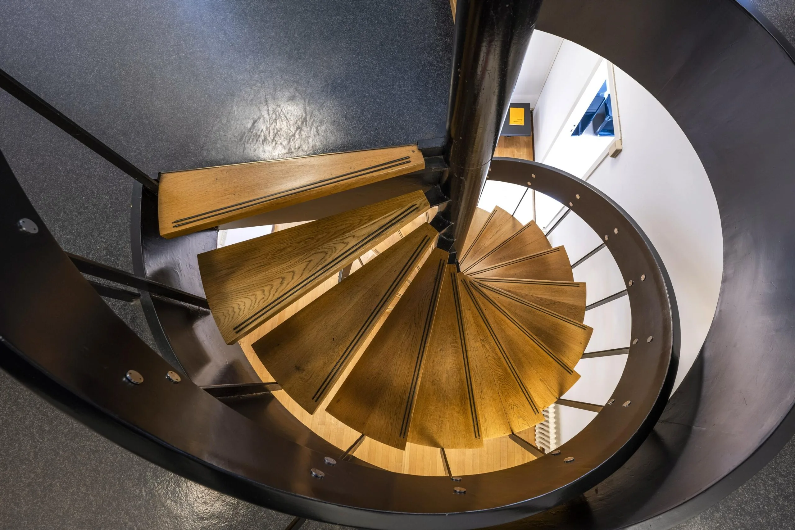 Houten wenteltrap met zwarte leuning in een modern interieur aan de Herengracht.