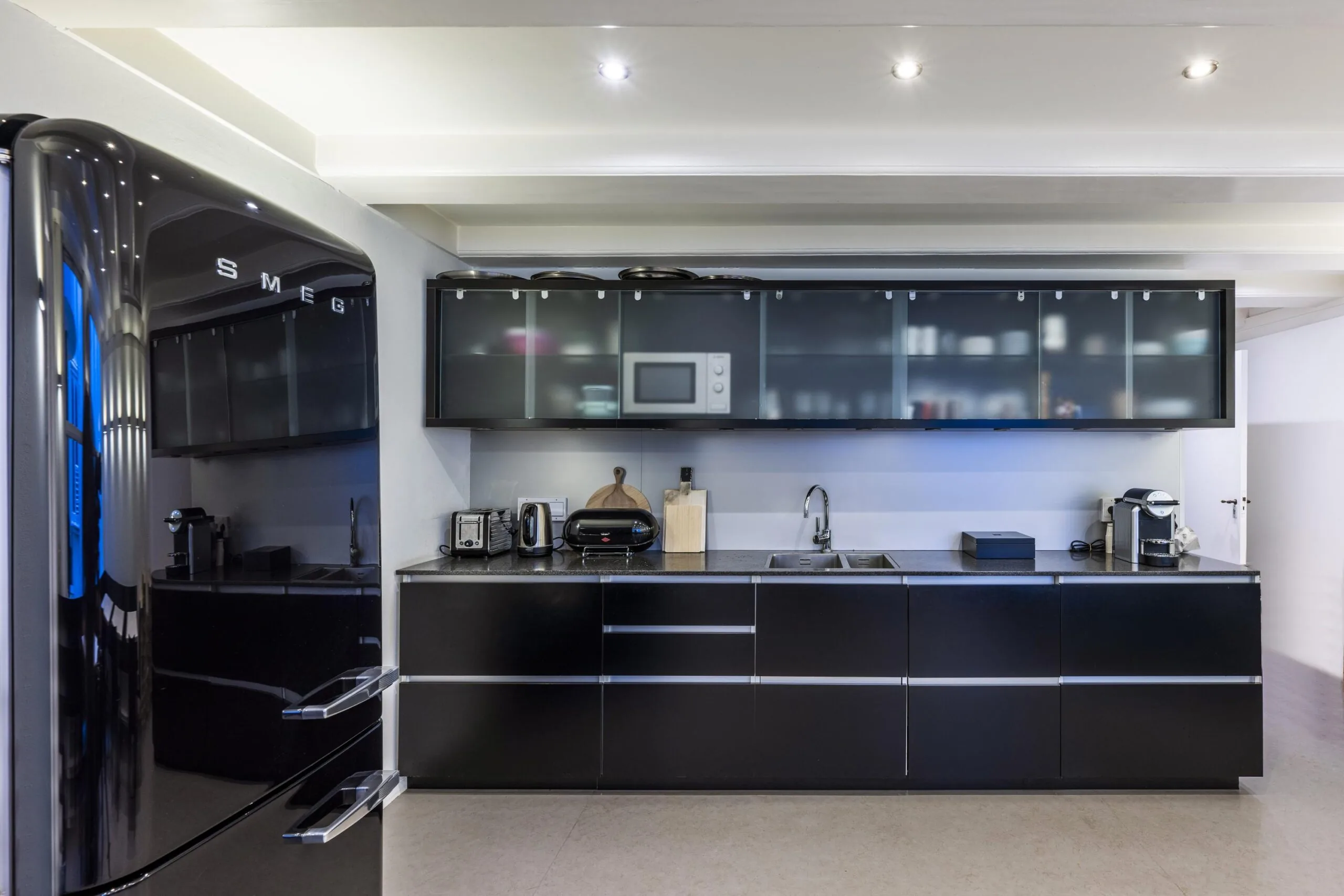 Moderne zwarte keuken met glanzende kasten, inbouwapparatuur en een Smeg-koelkast aan de Herengracht.