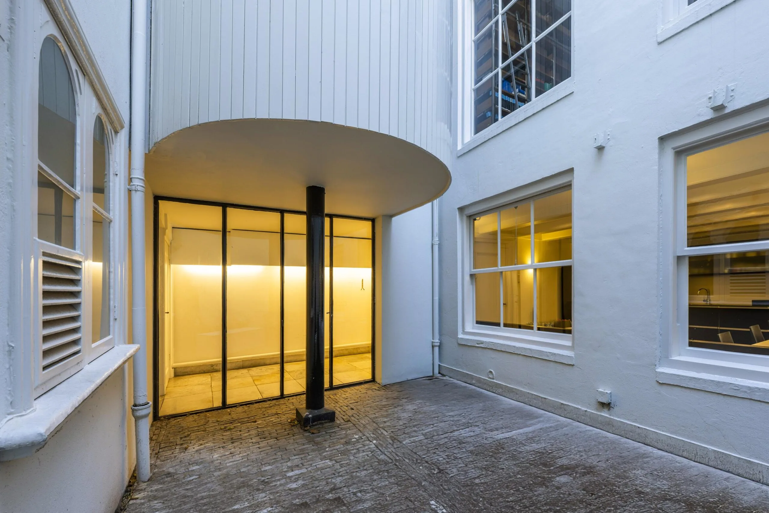 Binnenplaats van Herengracht 261 met moderne glazen entree en omliggende witte gevels.