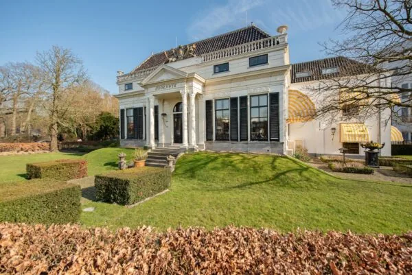 Witte klassieke villa met zuilen en de naam 'Hoornwyck' aan de Jan Thijssenweg, omgeven door een verzorgde tuin.