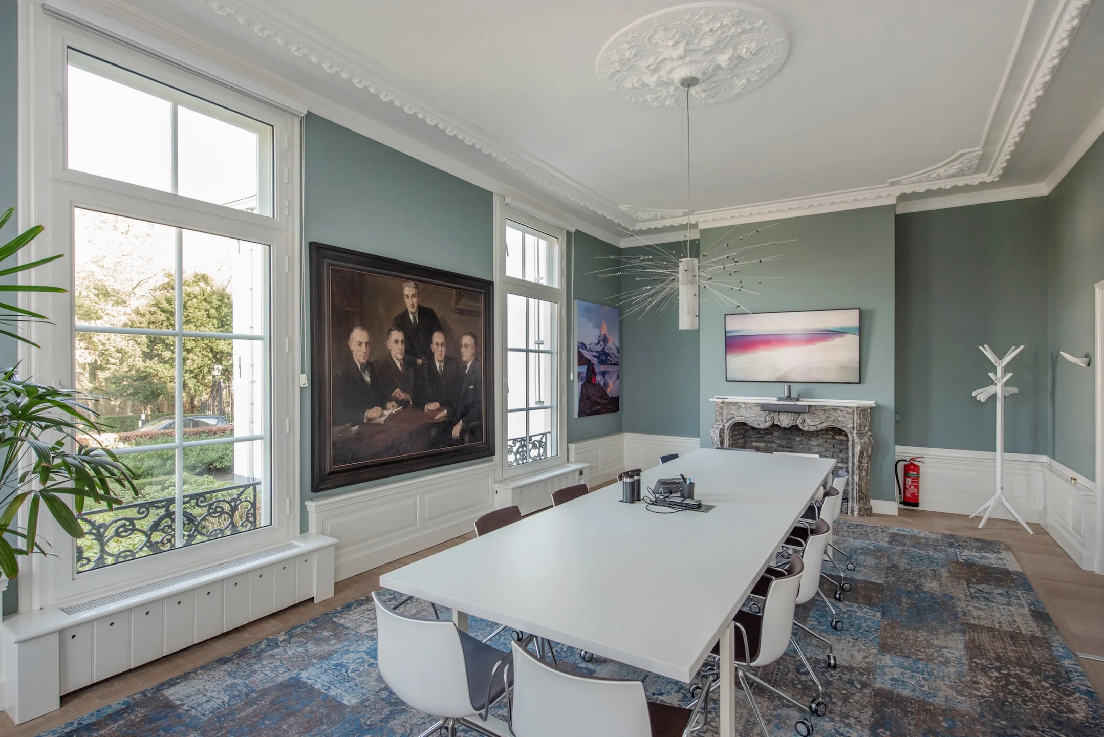 Vergaderruimte aan de Jan Thijssenweg met moderne inrichting, grote ramen, kunst aan de muur en een sierlijk plafond.