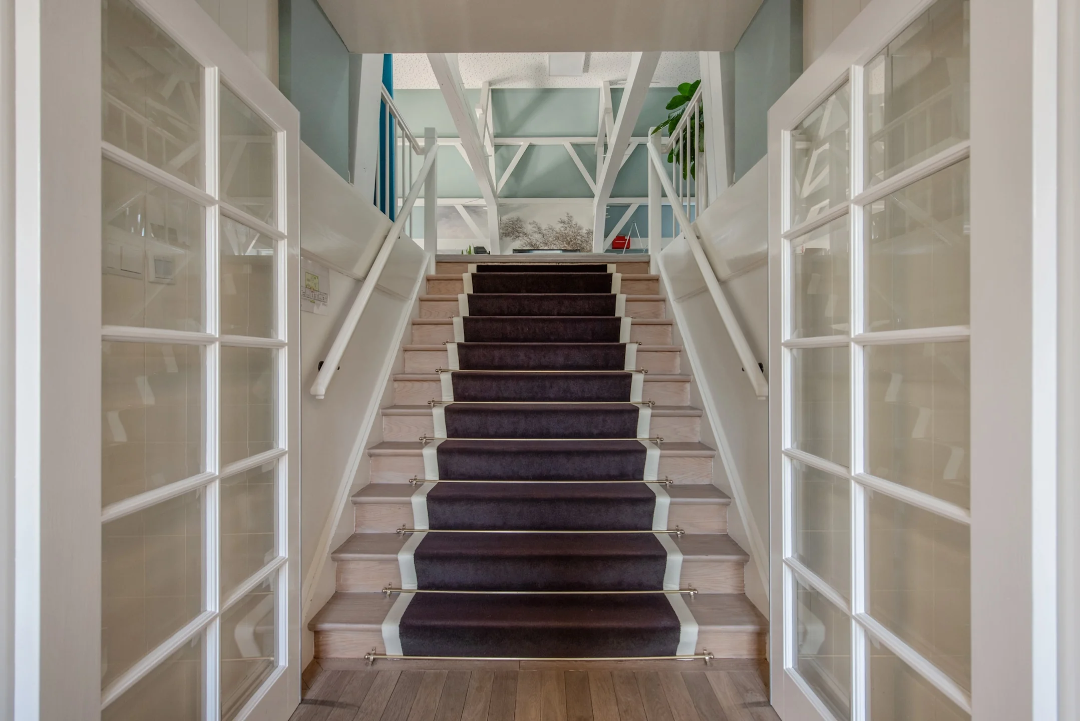 Trap met paarse loper tussen twee witte deuren in een modern interieur aan de Jan Thijssenweg.