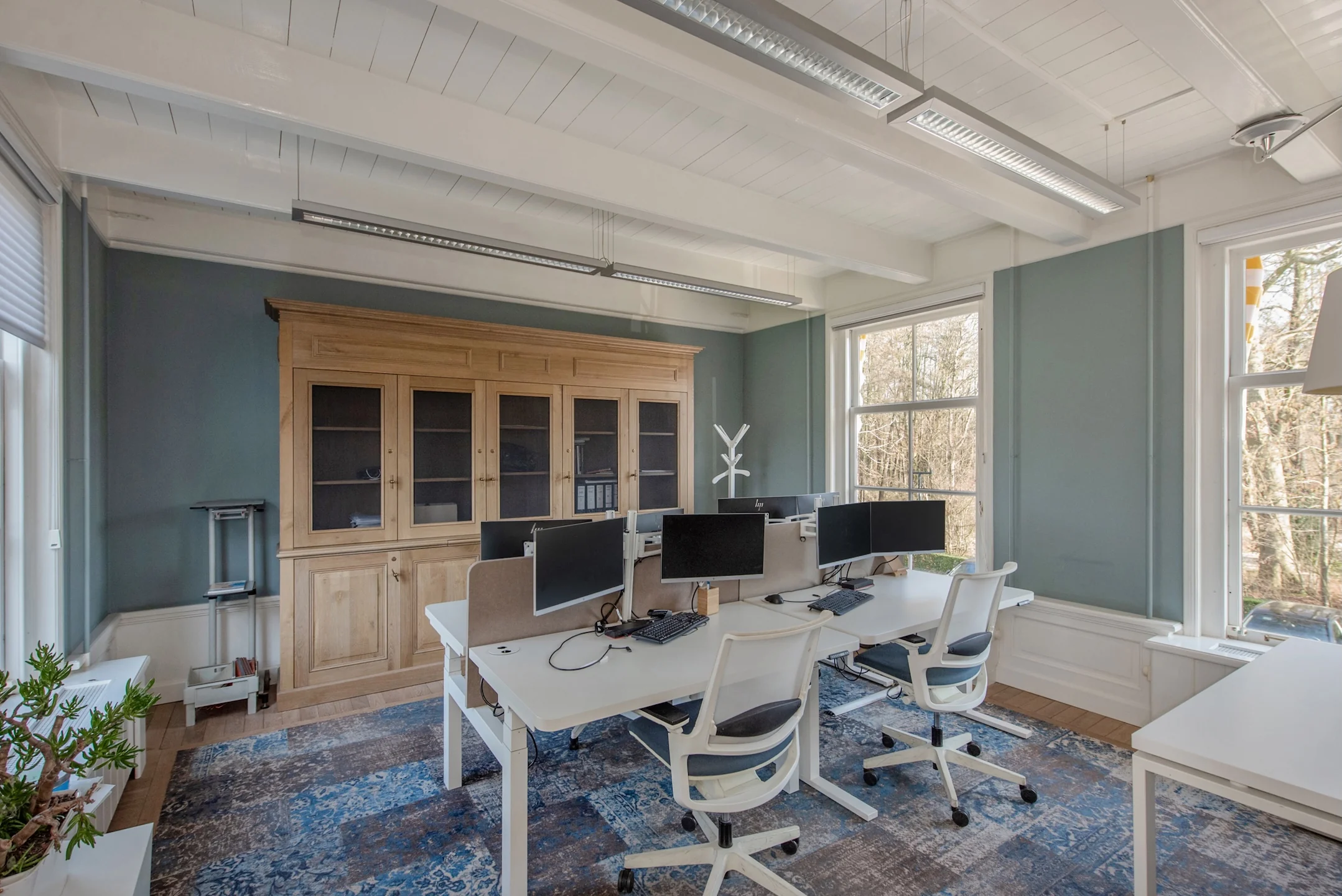 Modern ingerichte kantoorruimte aan de Jan Thijssenweg met werkplekken, bureaustoelen, computers en een grote houten kast.