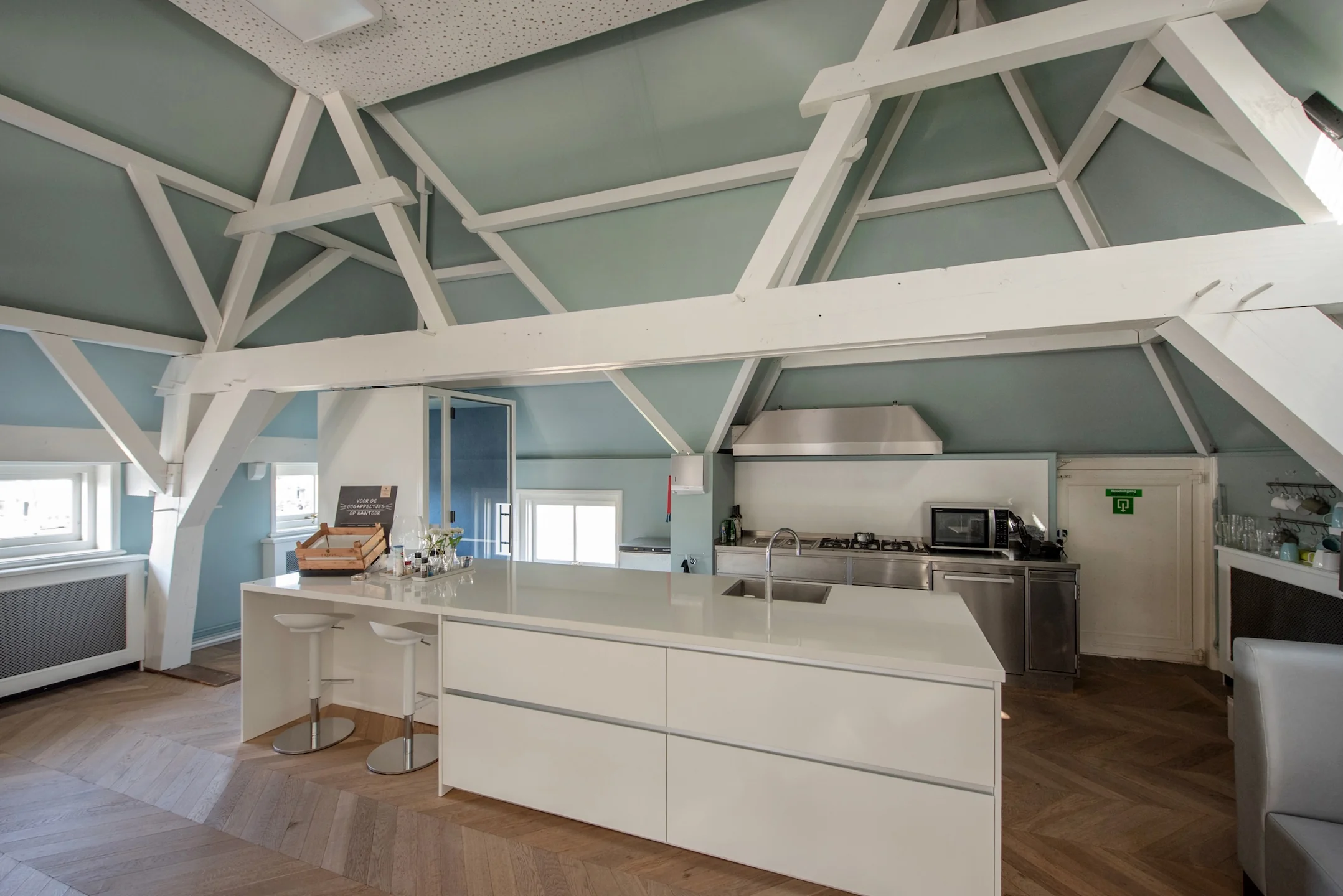 Moderne keuken met kookeiland in een karakteristiek pand aan de Jan Thijssenweg, met zichtbare houten balken en hoog plafond.