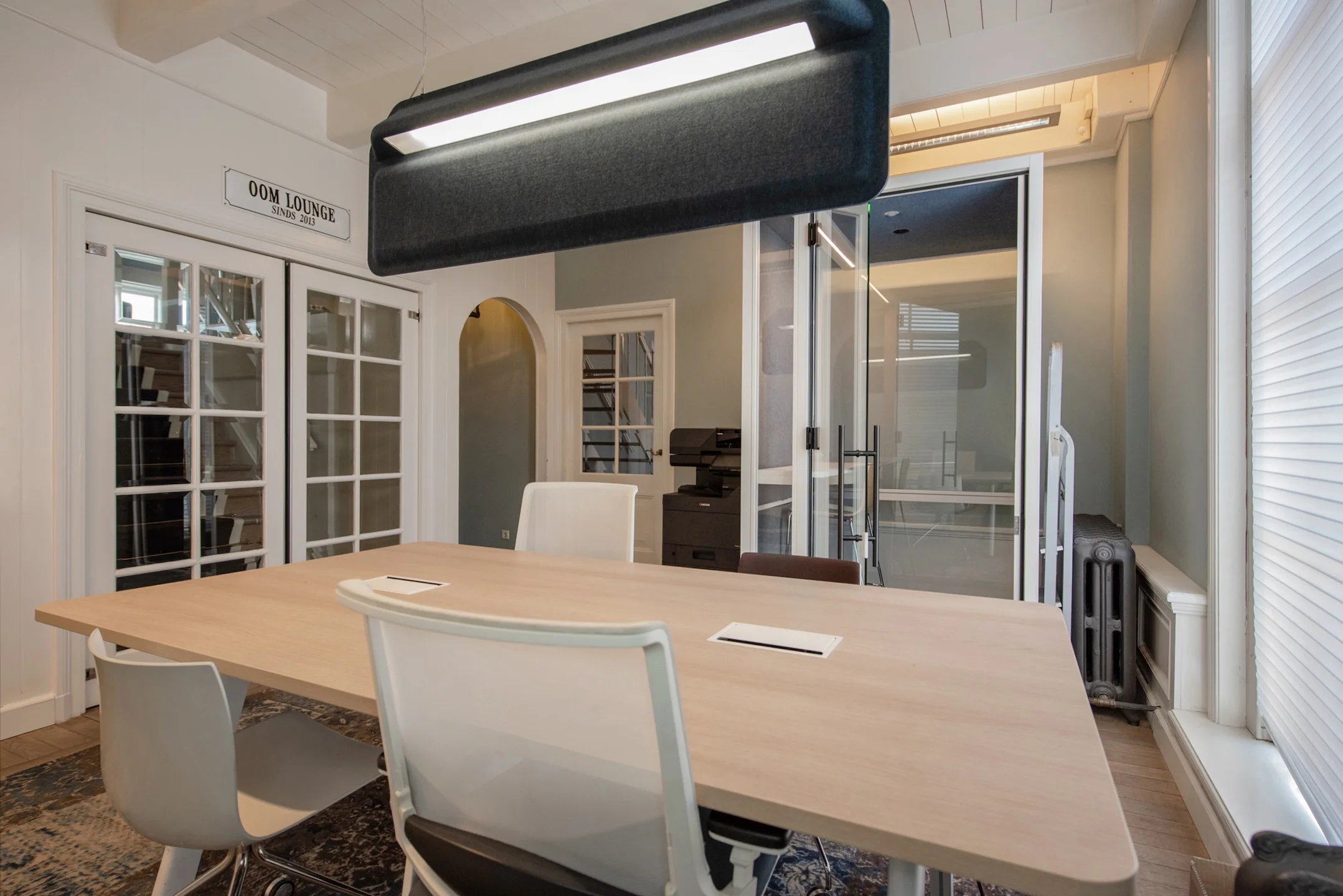 Moderne vergaderruimte aan de Jan Thijssenweg met houten tafel, diverse stoelen en glazen scheidingswand.