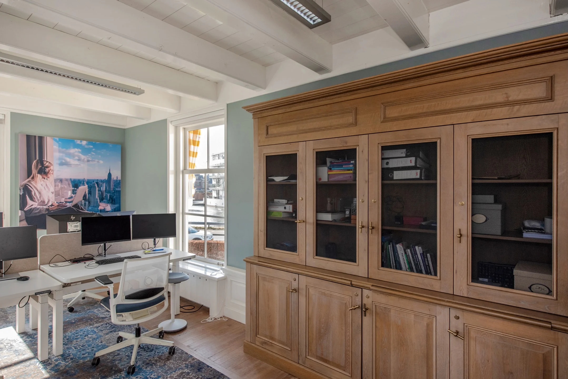 Moderne kantoorruimte aan de Jan Thijssenweg met werkplekken, een grote houten boekenkast en een raam met uitzicht op buiten.