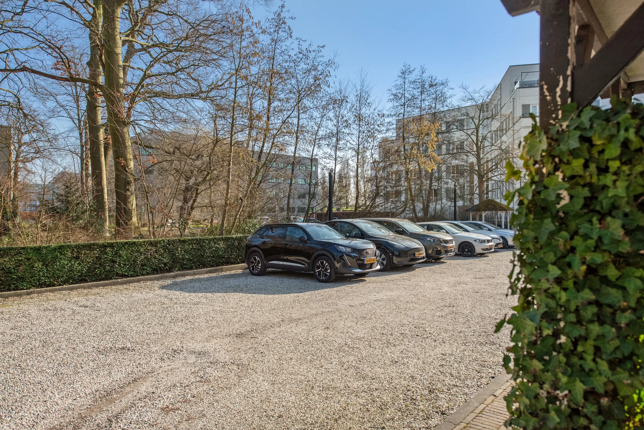 Parkeerplaats aan de Jan Thijssenweg met geparkeerde auto’s en omringende bebouwing op een zonnige dag.