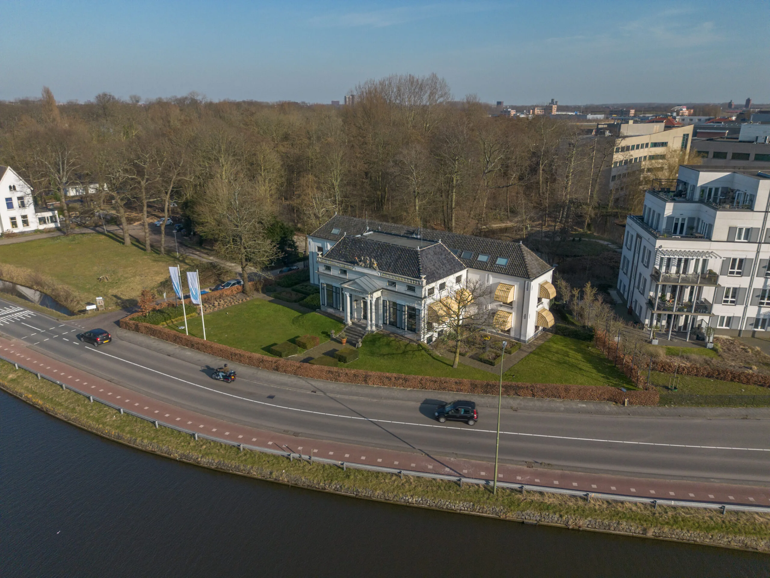 Luchtfoto van een herenhuis aan de Jan Thijssenweg in Arnhem, gelegen langs een kanaal en omringd door kantoren en natuur.