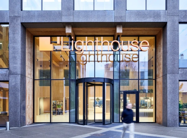 De hoofdingang van het moderne kantoorgebouw 'Lighthouse' aan de Basisweg met glazen gevel en houten interieurdetails.