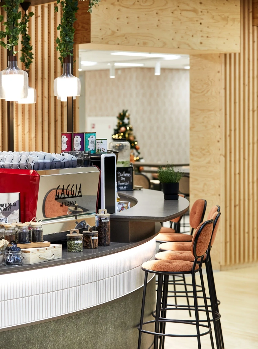 Moderne koffietbar met Gaggia-espressomachine, kruidenpotjes en oranje barkrukken in een sfeervol ingericht interieur.