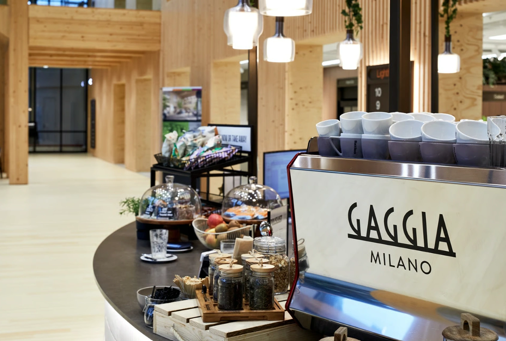 Koffiebar met Gaggia Milano espressomachine en diverse etenswaren in een modern houten interieur aan de Basisweg.