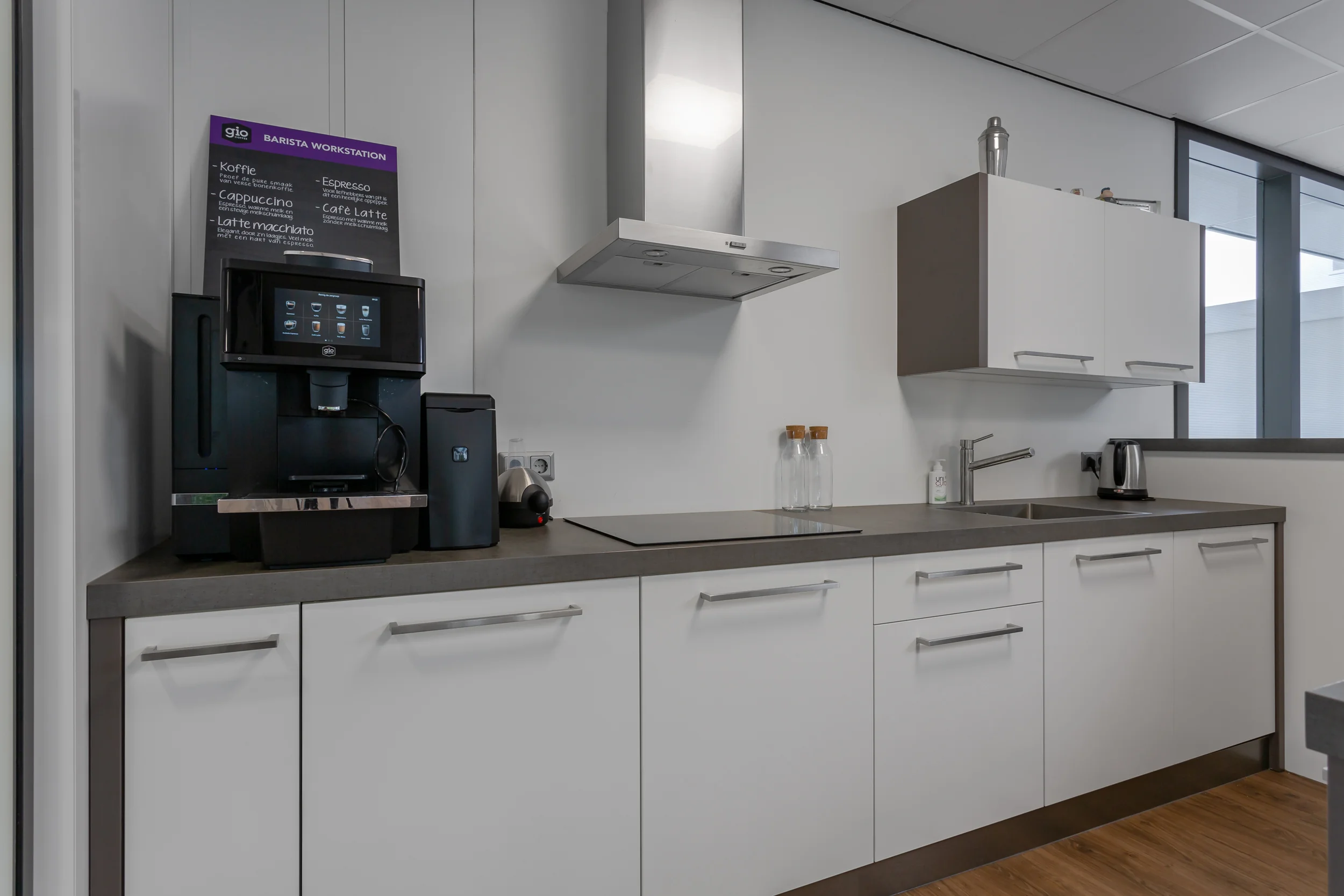 Moderne kantoorkeuken met koffieautomaat, kookplaat, spoelbak en opbergkasten aan de Energieweg.