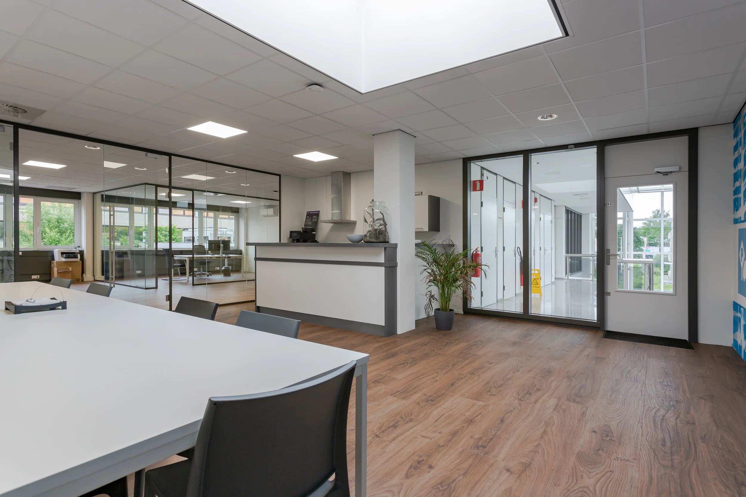 Moderne kantoorruimte aan de Energieweg met glazen vergaderruimtes, receptiebalie en houten vloer.