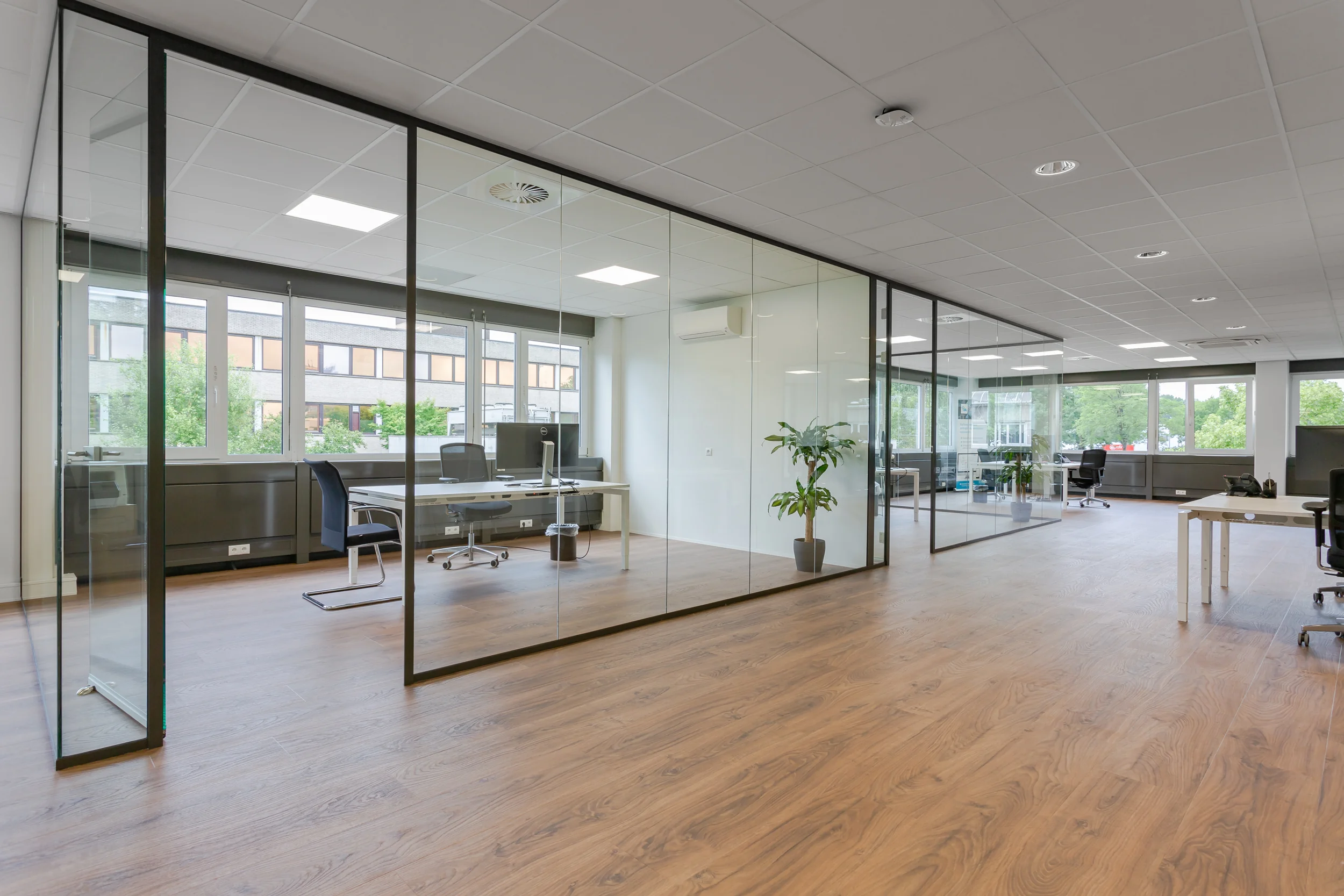 Moderne kantoorruimte aan de Energieweg met glazen vergaderruimtes, houten vloer en grote ramen.