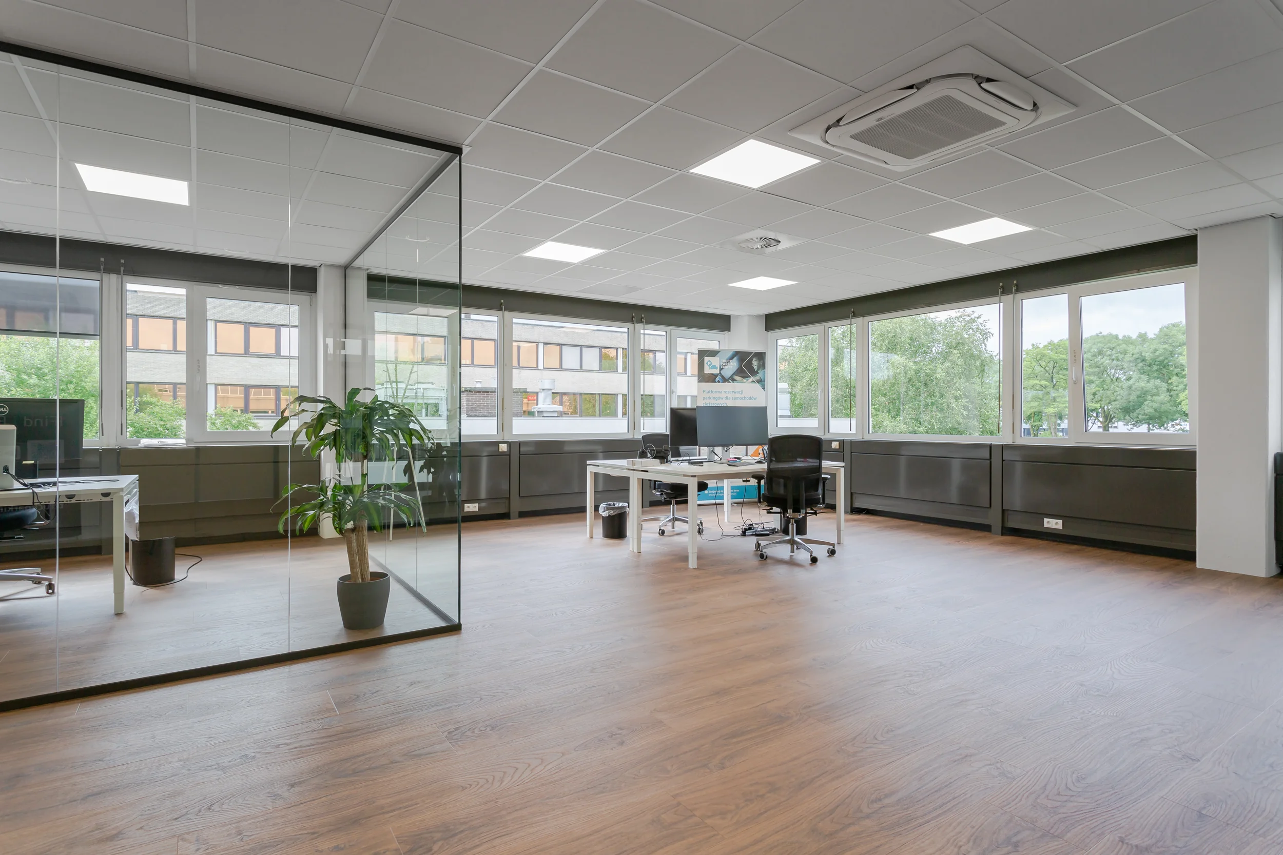 Modern en licht kantoorpand aan de Energieweg met glazen vergaderruimte, houten vloer en werkplekken bij grote ramen.
