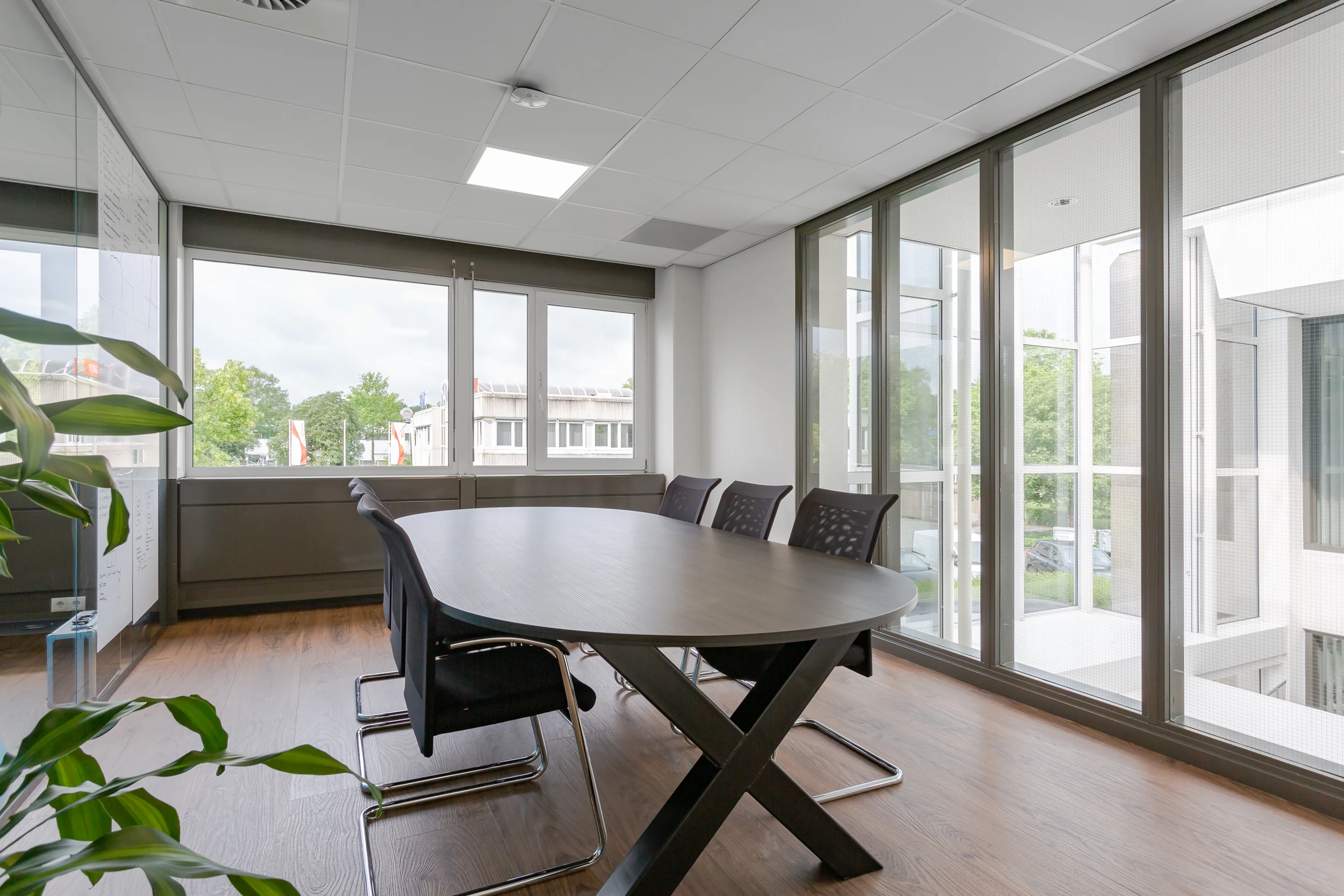 Vergaderruimte met ovale tafel, zes stoelen en grote ramen aan de Energieweg.