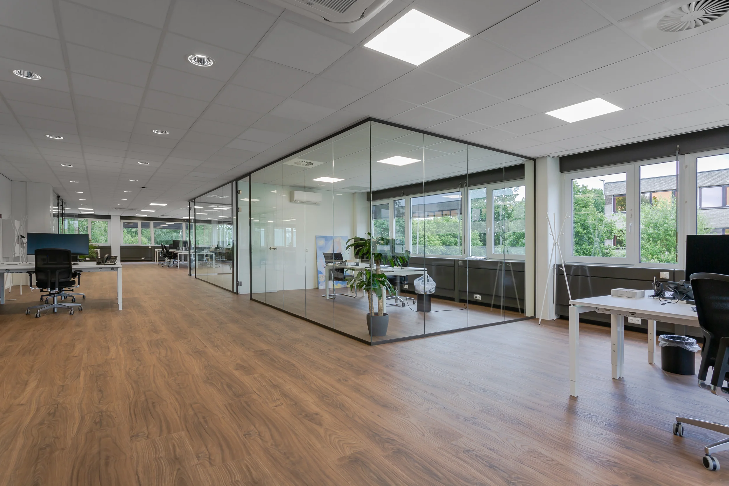 Modern open kantoorpand aan de Energieweg met glazen vergaderruimte en houten vloer.