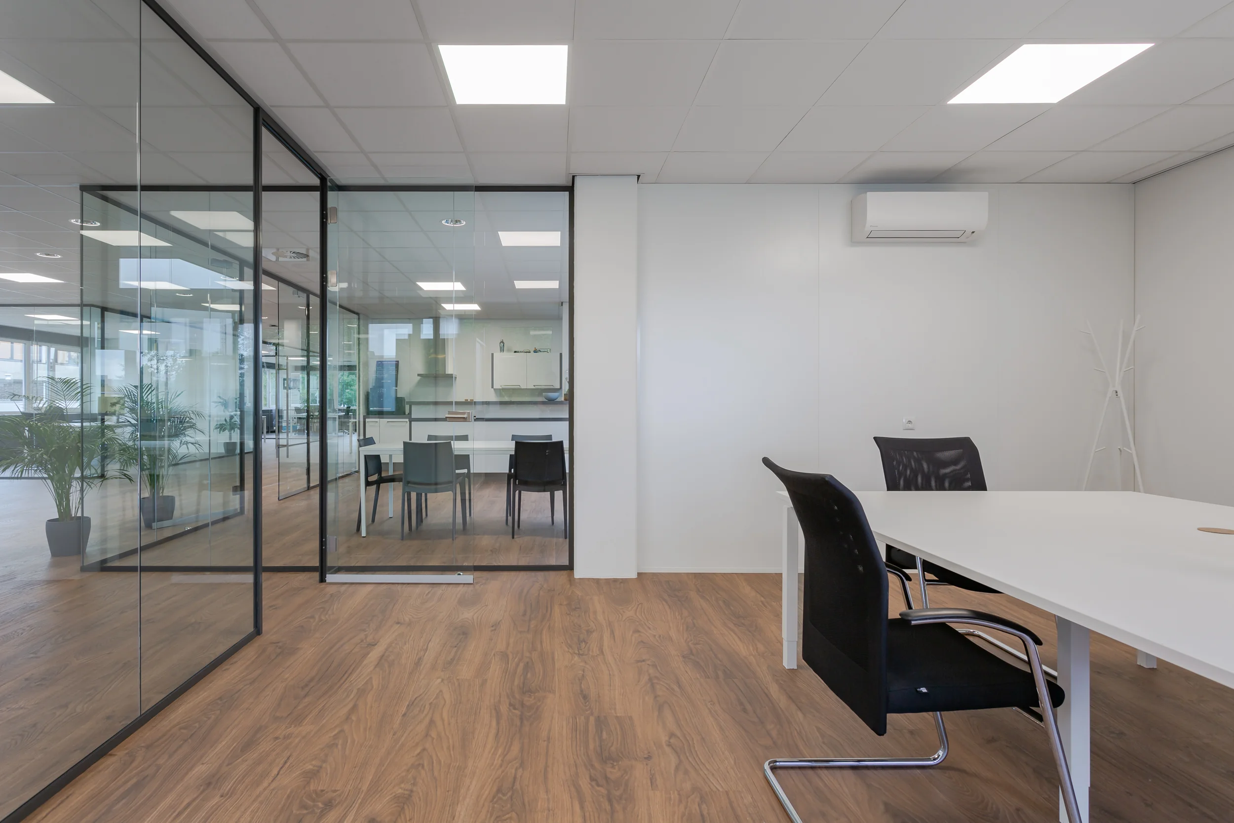 Moderne en lichte kantoorruimte aan de Energieweg met glazen wanden, houten vloer en minimalistisch meubilair.