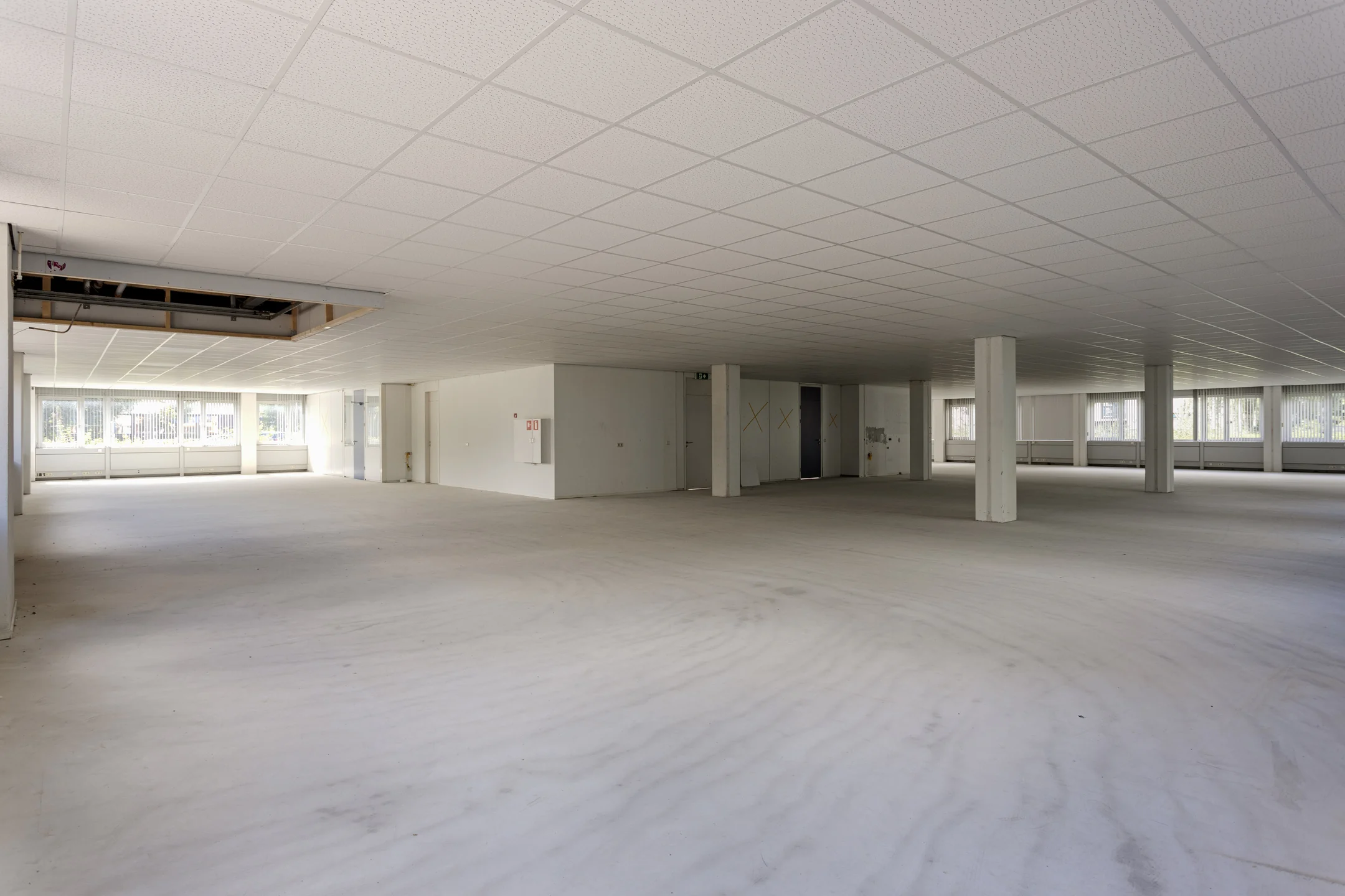 Leegstaand kantoorruimte-interieur aan de Energieweg met systeemplafond en grote raampartijen.
