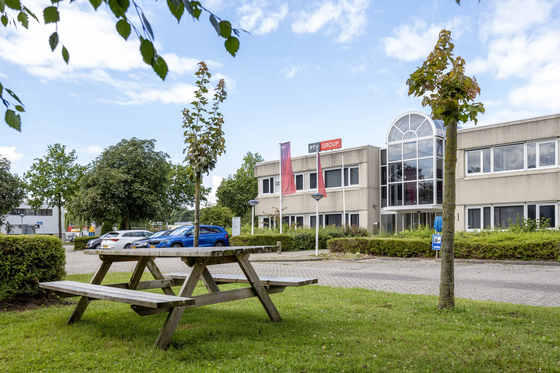 Bedrijfsgebouw van PTV Group aan de Energieweg met parkeerplaatsen en picknicktafel op het grasveld.