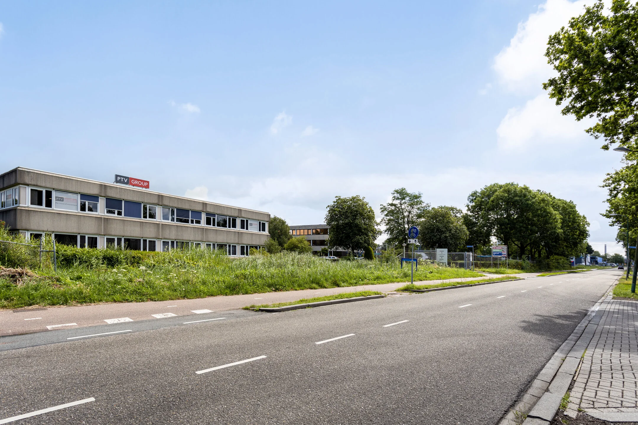 Kantoorpand van PTV Group aan de Energieweg met een lege weg en groenstrook op de voorgrond.