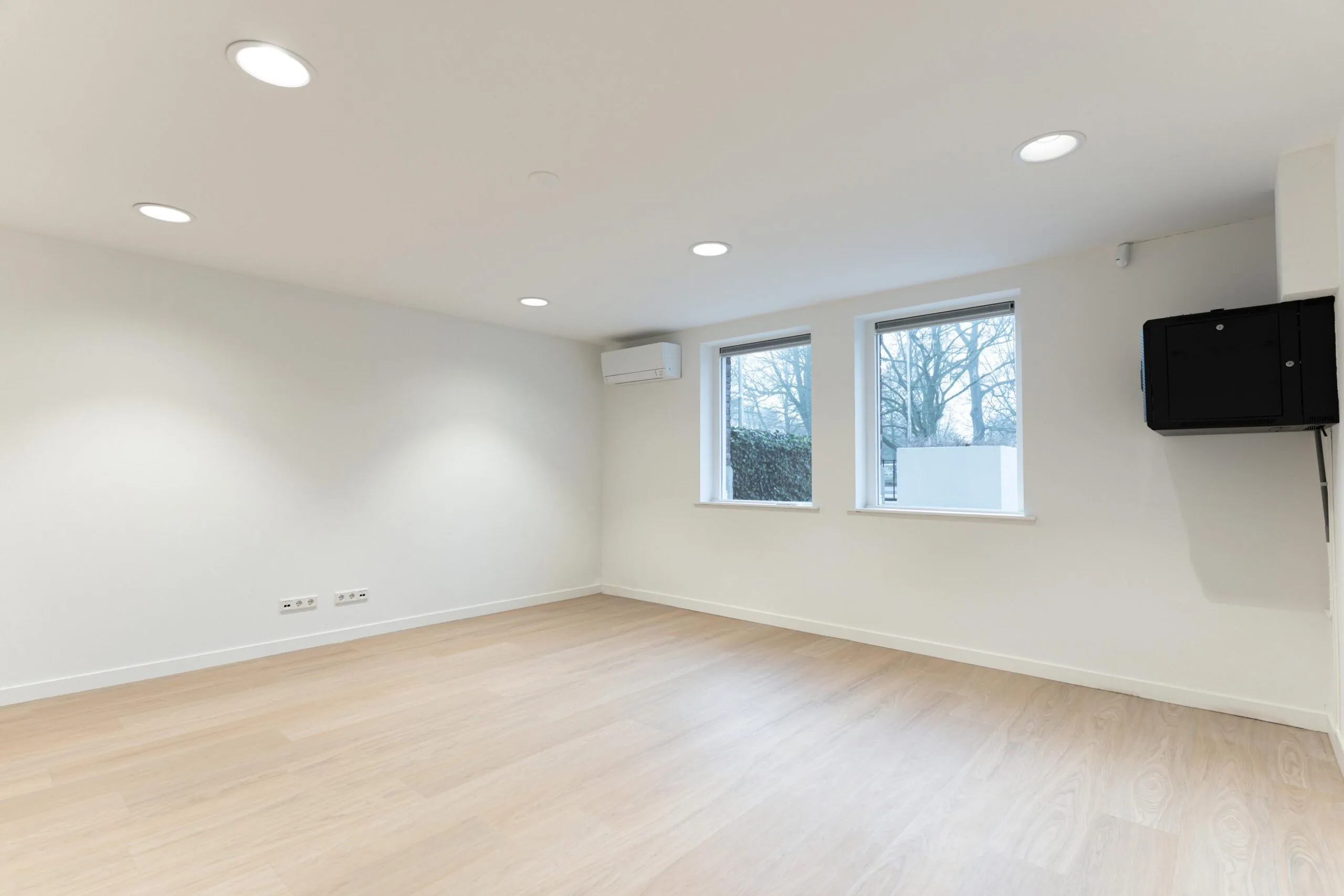 Lichte, lege kamer aan de Biltstraat met houten vloer, twee ramen, airco-unit en wandkast.