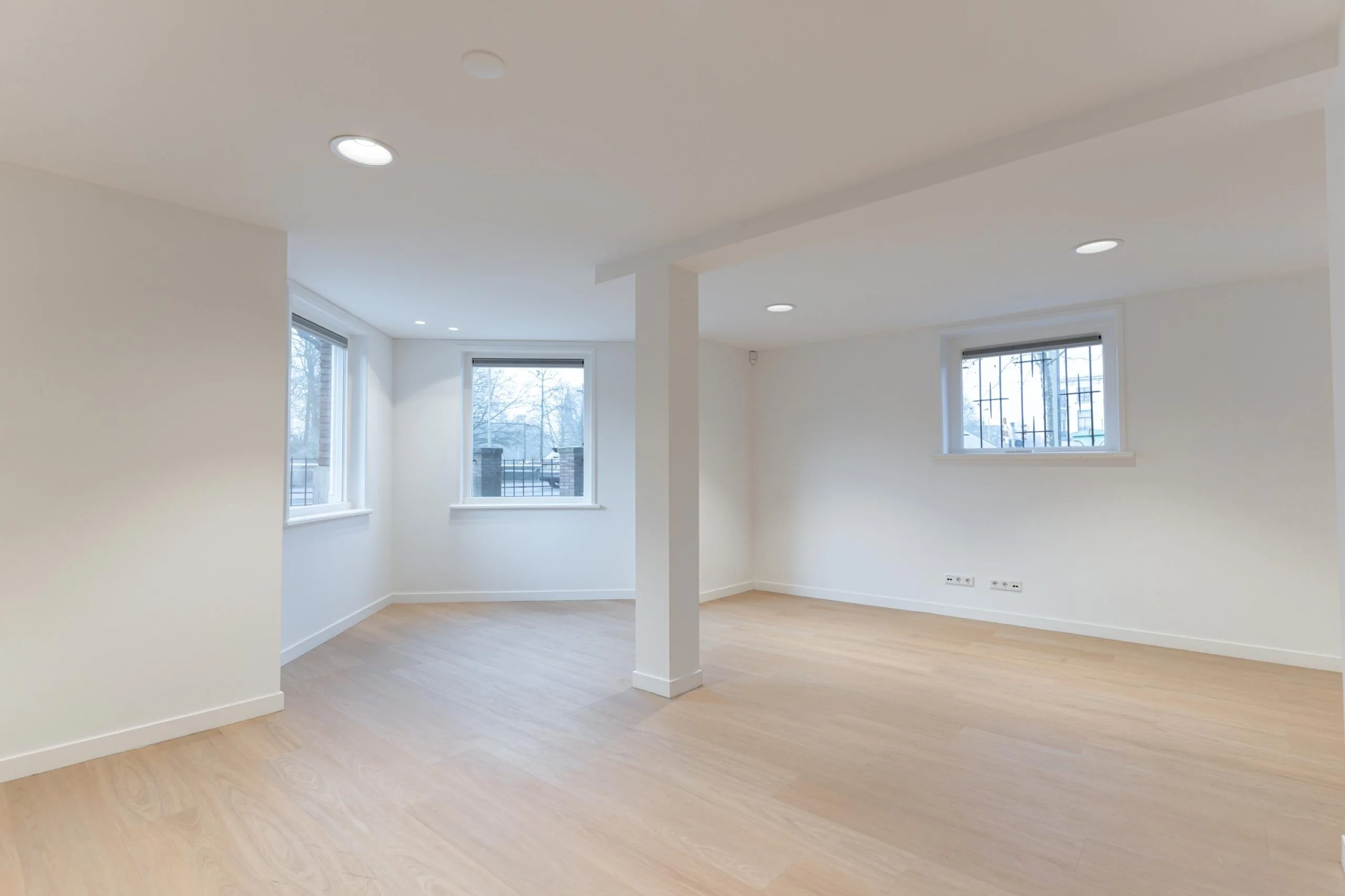 Lichte, lege kamer met grote ramen en een houten vloer aan de Biltstraat.