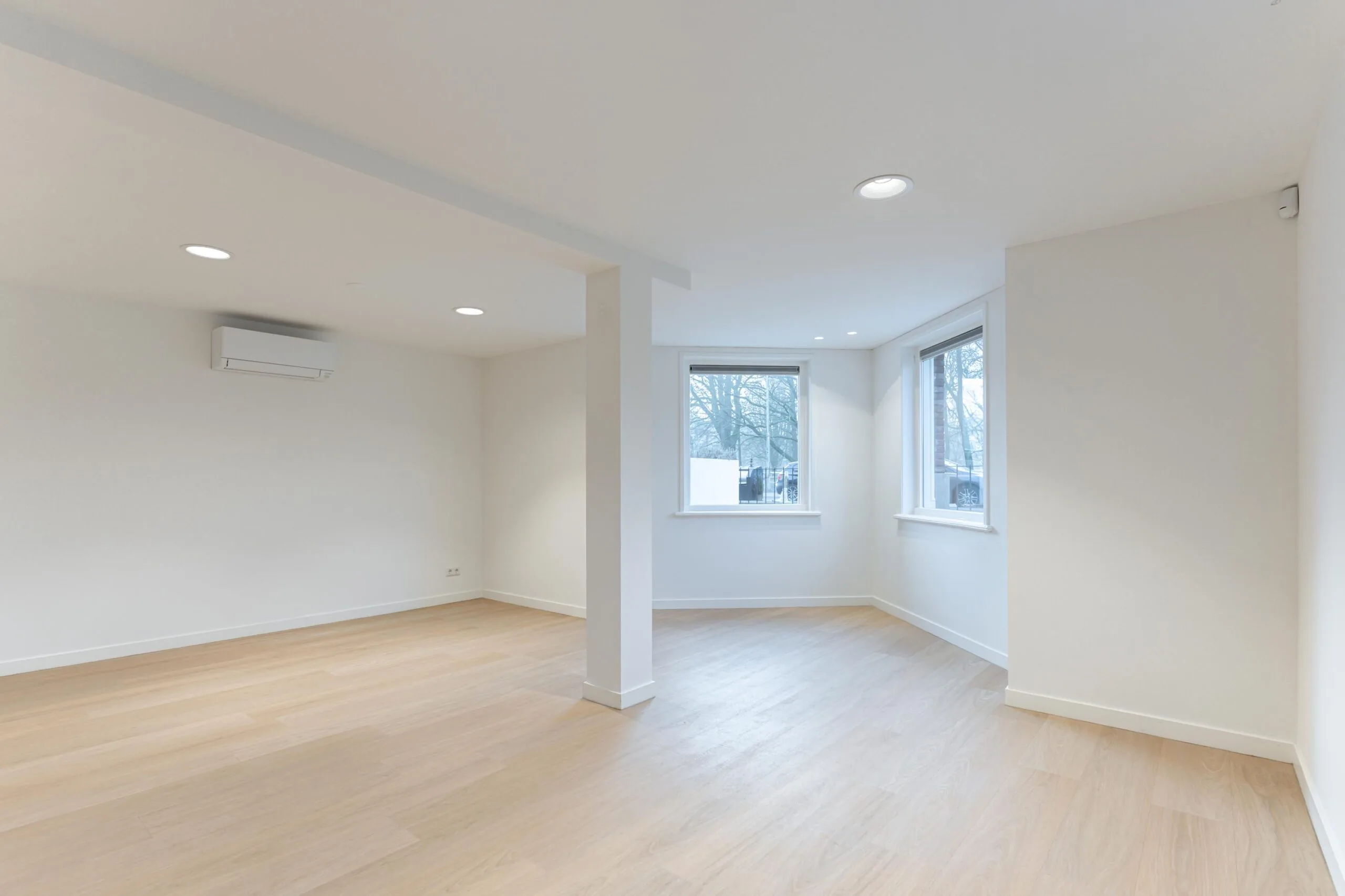Licht en modern afgewerkte woonruimte aan de Biltstraat met houten vloer, witte muren en grote ramen.