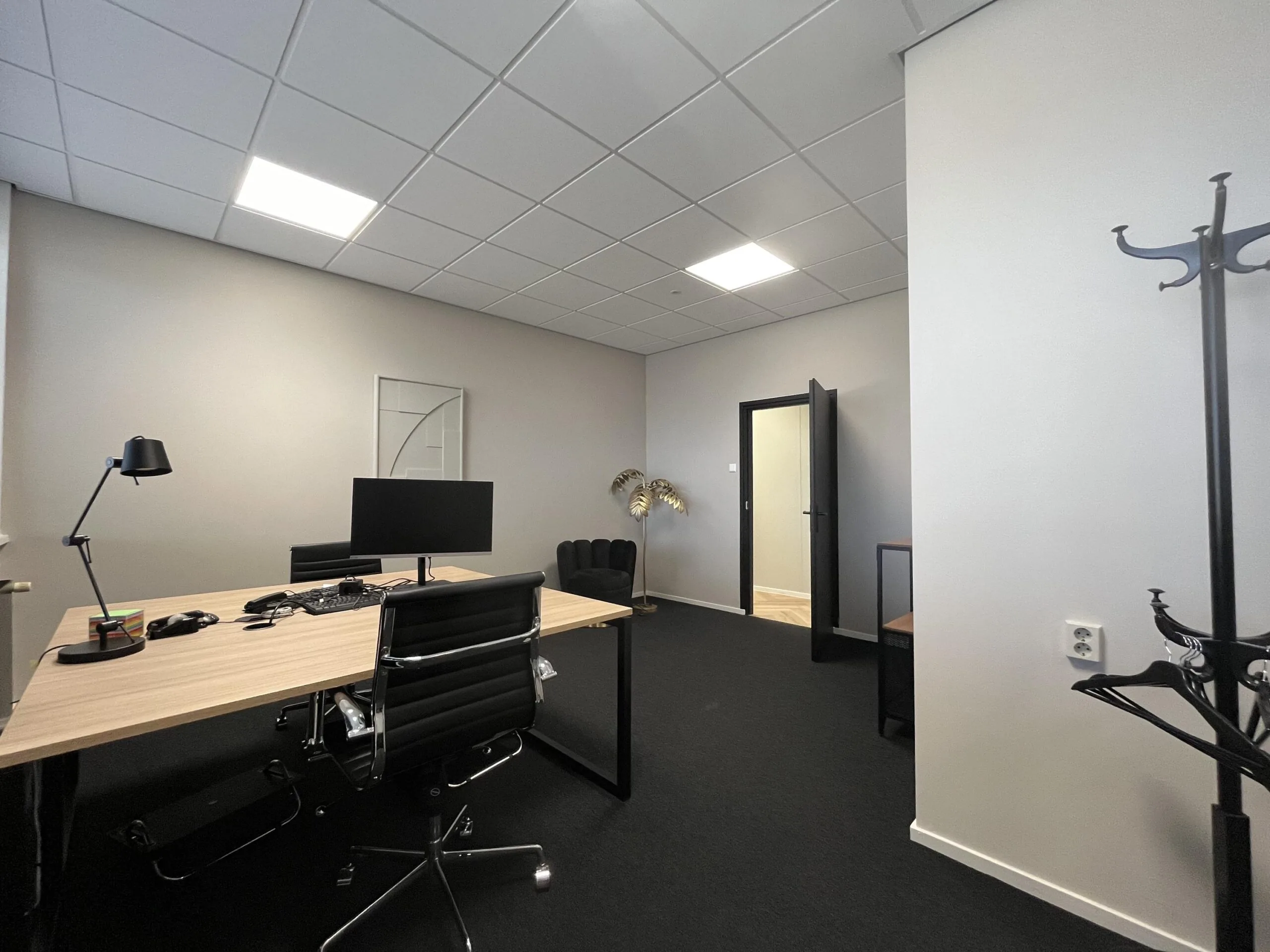 Modern ingericht kantoor met houten bureau, zwarte bureaustoelen en minimalistische decoratie aan de Industrieweg.