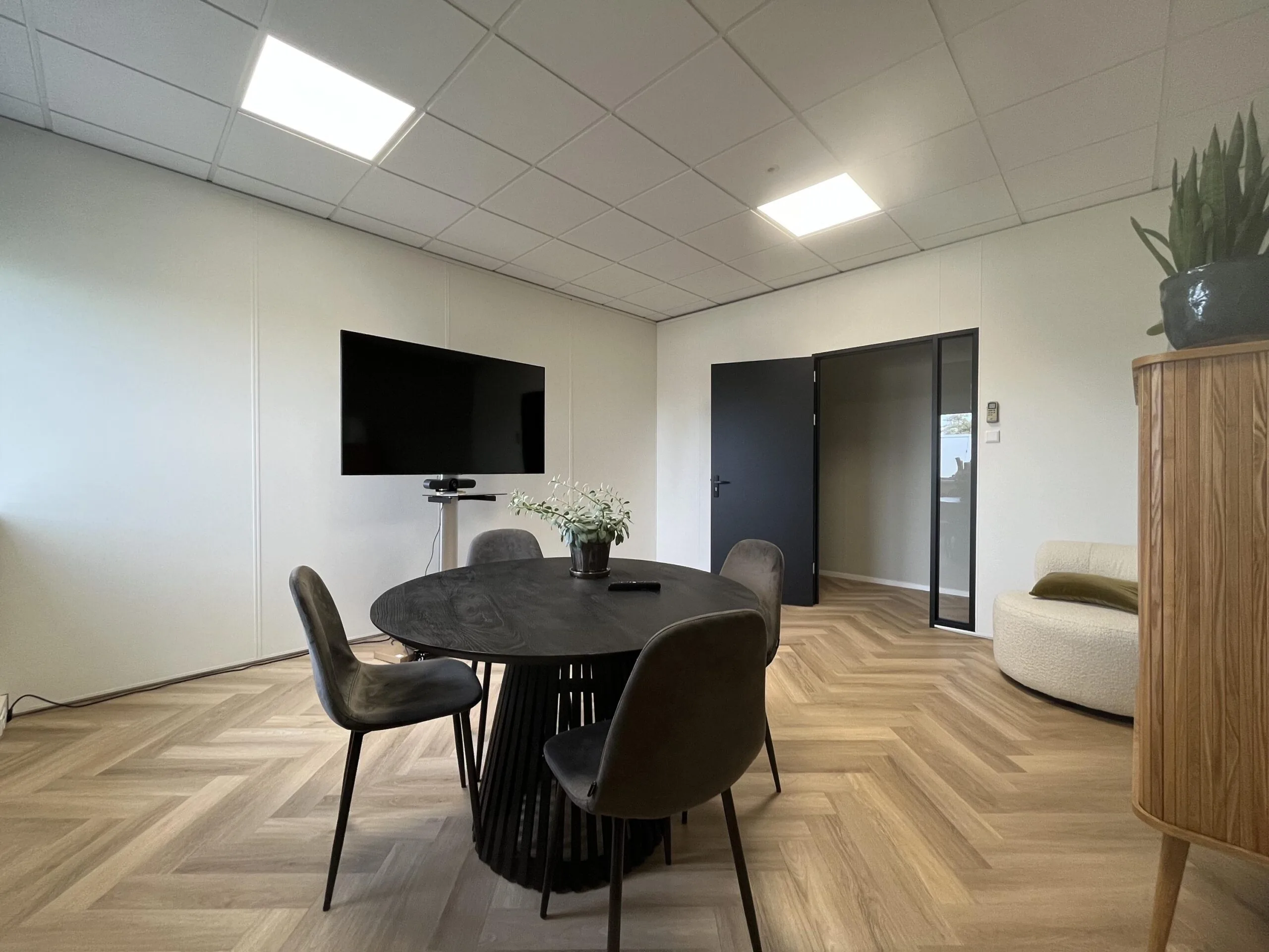 Moderne vergaderruimte aan de Industrieweg met ronde tafel, flatscreen, en eigentijdse inrichting.