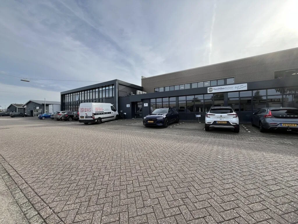 Bedrijfsgebouw aan de Industrieweg met geparkeerde auto's en een bestelbus van BAS voor de ingang van Van Dillen Beheer.