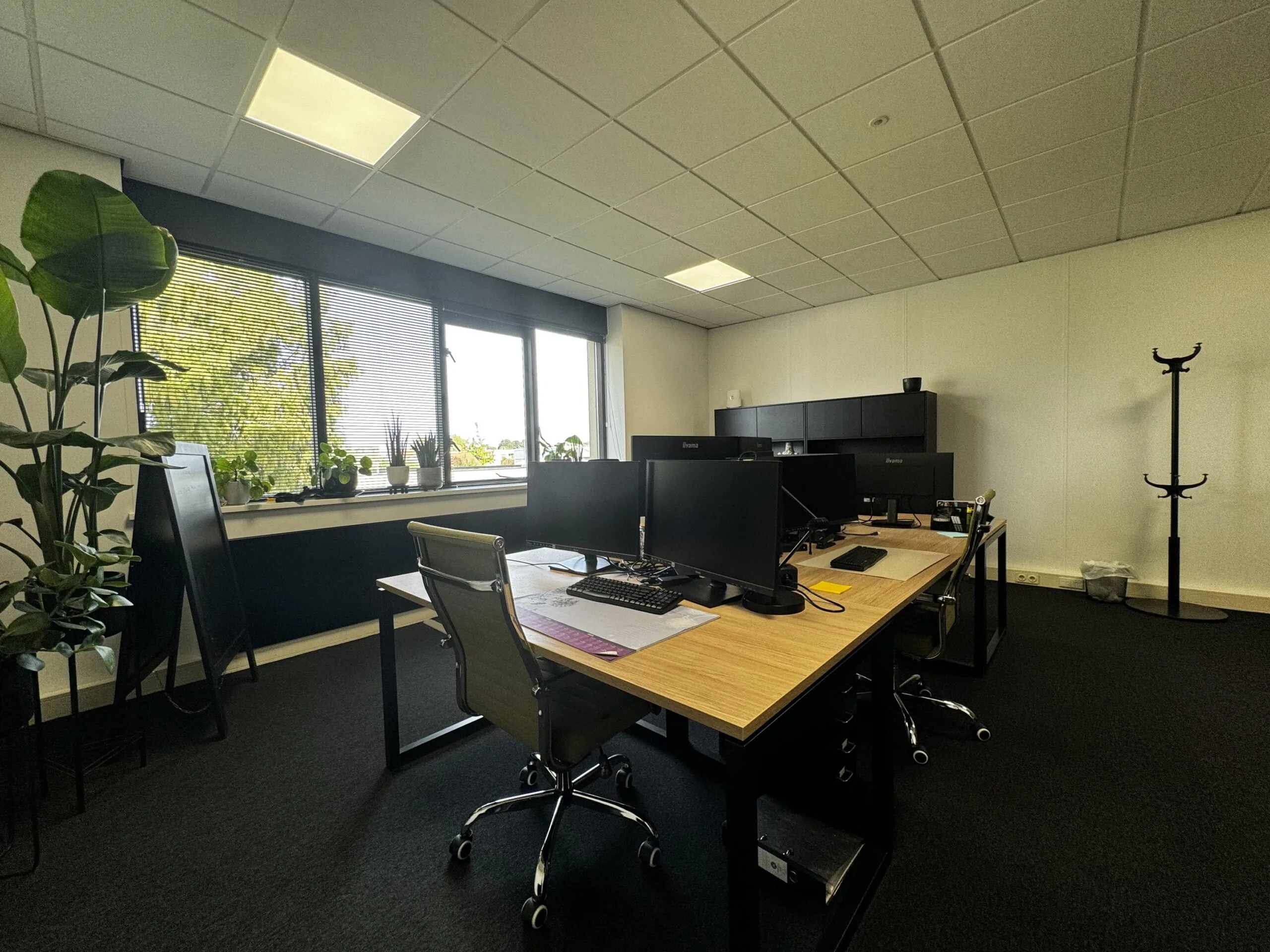 Moderne kantoorruimte aan de Industrieweg met bureaus, computers, planten en grote ramen met uitzicht op groen.
