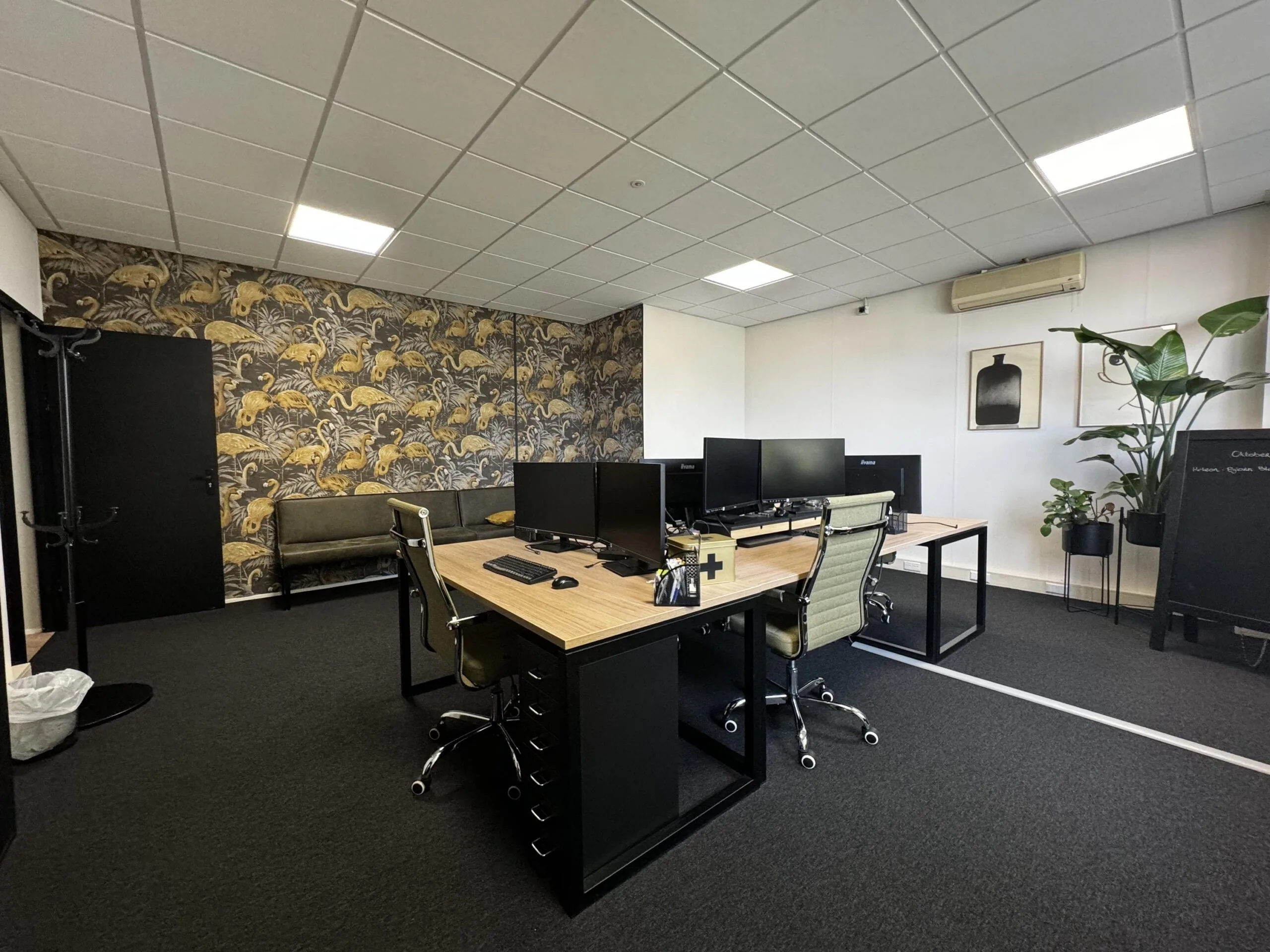 Modern ingericht kantoor op de Industrieweg met werkplekken, planten en een opvallende decoratieve muur.