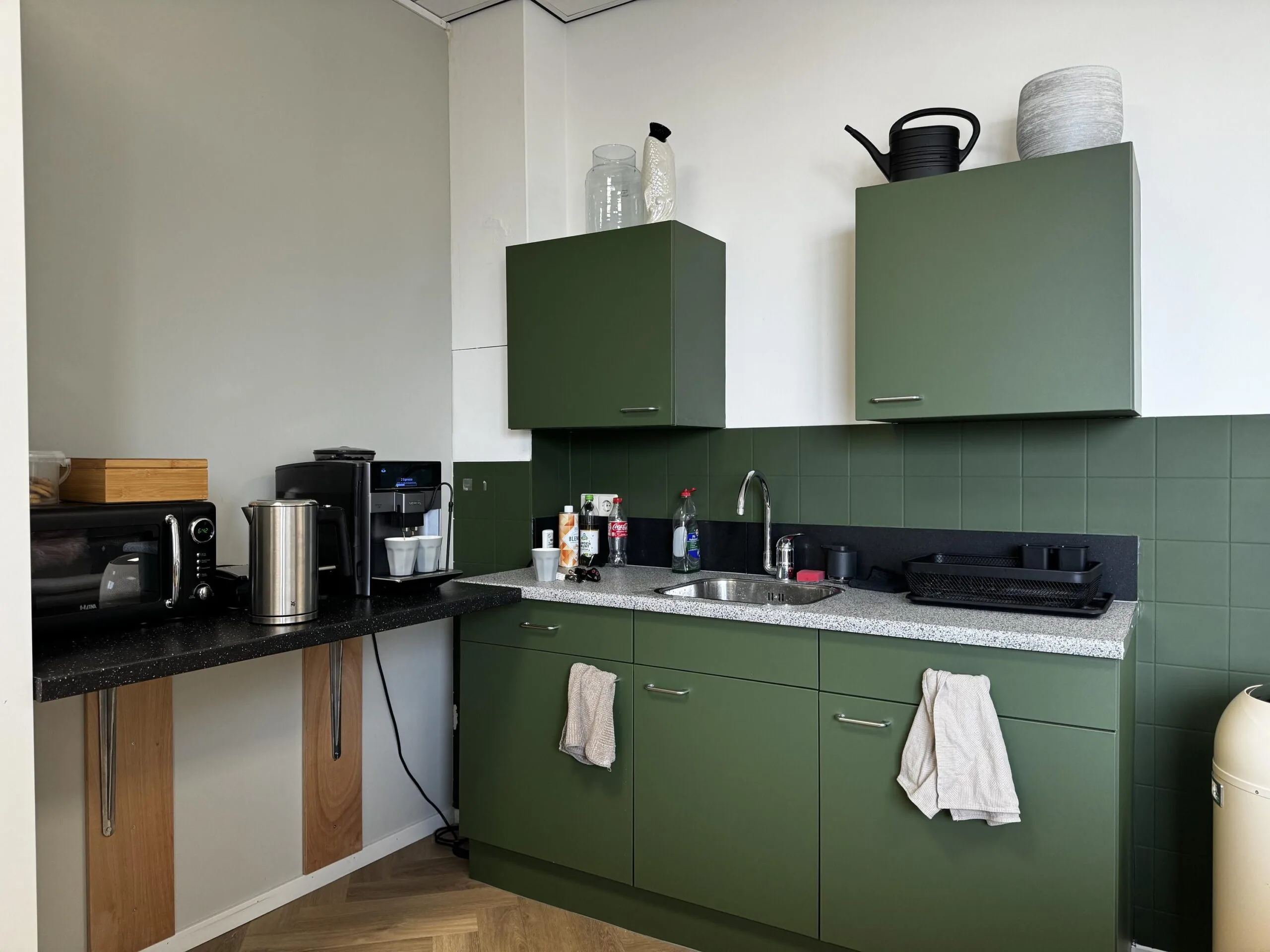 Groene kantoorpantry met koffiezetapparaat, magnetron, spoelbak en opbergruimte aan de Industrieweg.