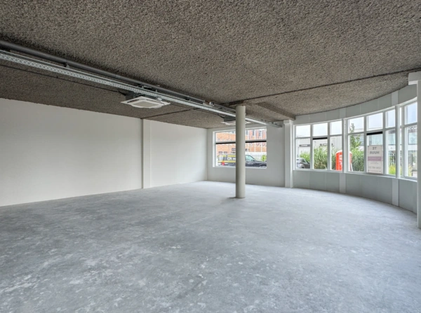 Leegstaand bedrijfs- of kantoorruimte aan de Nijverheidslaan met grote ramen en een betonnen vloer.