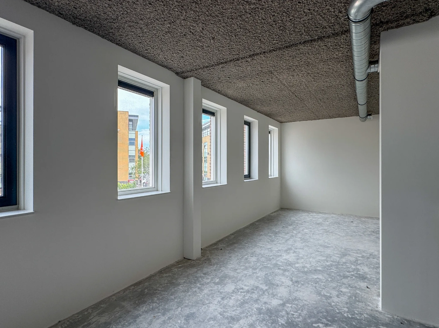 Leegstaand industrieel kantoorpand aan de Nijverheidslaan met vijf ramen en zicht op omliggende gebouwen.