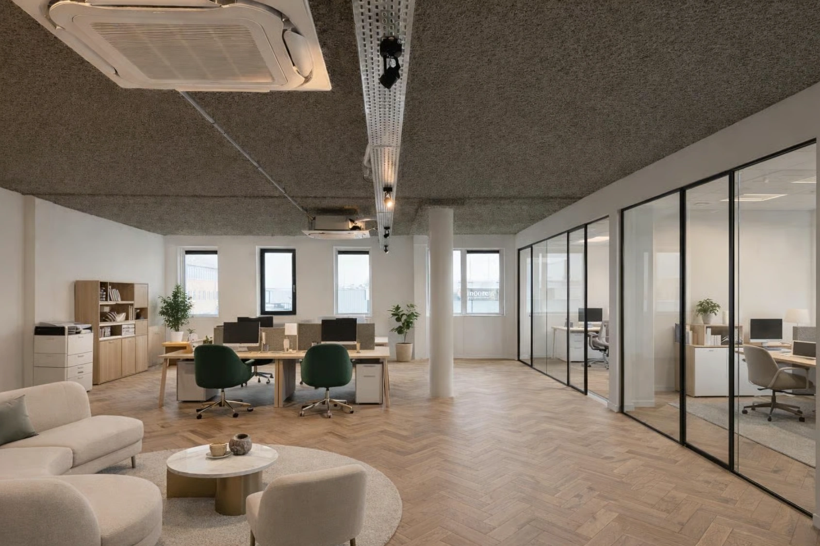 Modern kantoorinterieur aan de Nijverheidslaan met open werkplekken, glazen vergaderruimtes en een zithoek met ronde tafel.