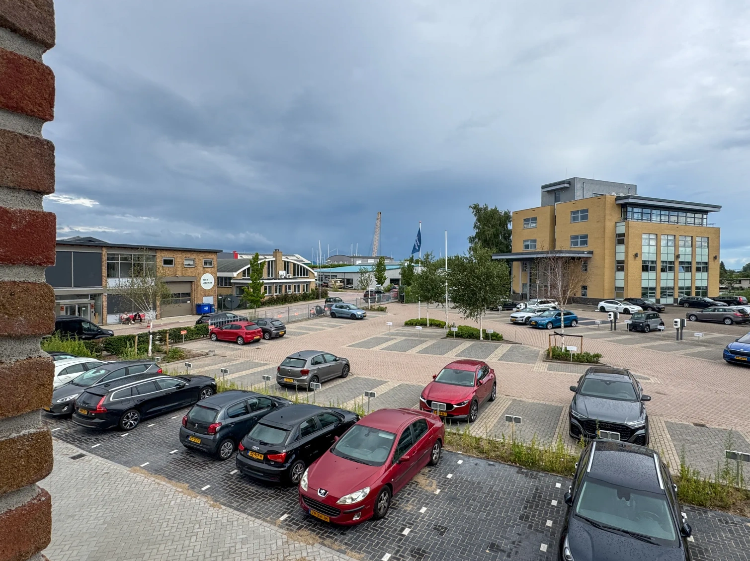 Overzicht van een parkeerterrein aan de Nijverheidslaan met verschillende geparkeerde auto’s en omliggende kantoorgebouwen.